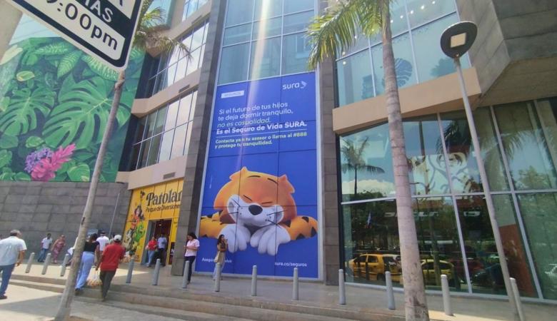Campaña publicitaria de SURA en fachada comercial con estrategia OOH e indoor